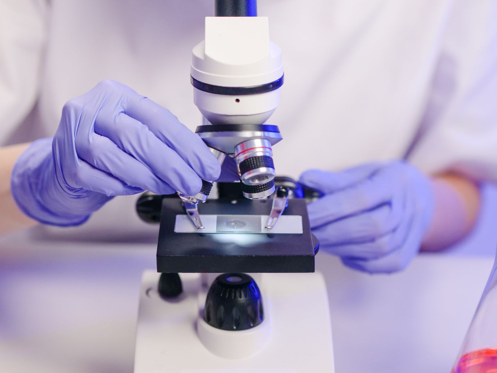 Scientist examining a specimen through a laboratory microscope
