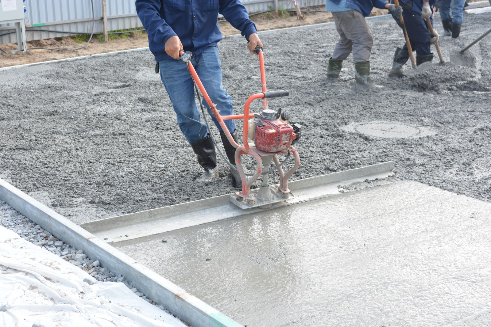 Concrete construction crew leveling freshly poured concrete
